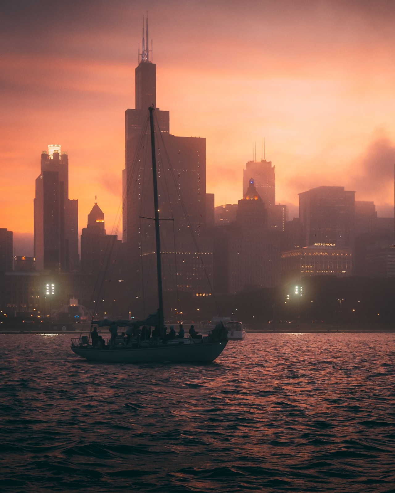 Mesmerizing view of the boat in the ocean and the silhouettes of high buildings during sunset